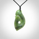 This picture shows a jade hook pendant, also called a hei-matau, carved for us in New Zealand jade. The cord is a four-plait, adjustable black coloured necklace.